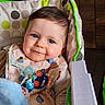 baby, bib, blanket, blue, cheerful, child, clothing, cute, face, happy, head, high_chair, home, indoor, infant, person, seat, smiling, toy, young_child