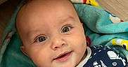 Lawton is registered to the contest to win money with this photo: baby, blanket, child, clothing, cozy, cute, expression, eyes, face, floor, hand, happy, head, indoor, infant, person, portrait, smiling, toddler, young