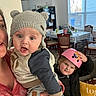Lawton joined the competition — help win amazing prizes! baby, child, adult, hat, knit_hat, helmet, pink_helmet, indoor, dining_room, table, chairs, window, person, clothing, jacket, sweater, hand, face, expression, home