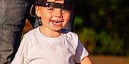 Christopher joined the competition — help win amazing prizes! toddler, child, boy, cap, white_tshirt, jeans, smiling, outdoor, sunlight, grass, person, adult, hand, happy, portrait, casual_clothing, nature, daylight, headwear, background_blur