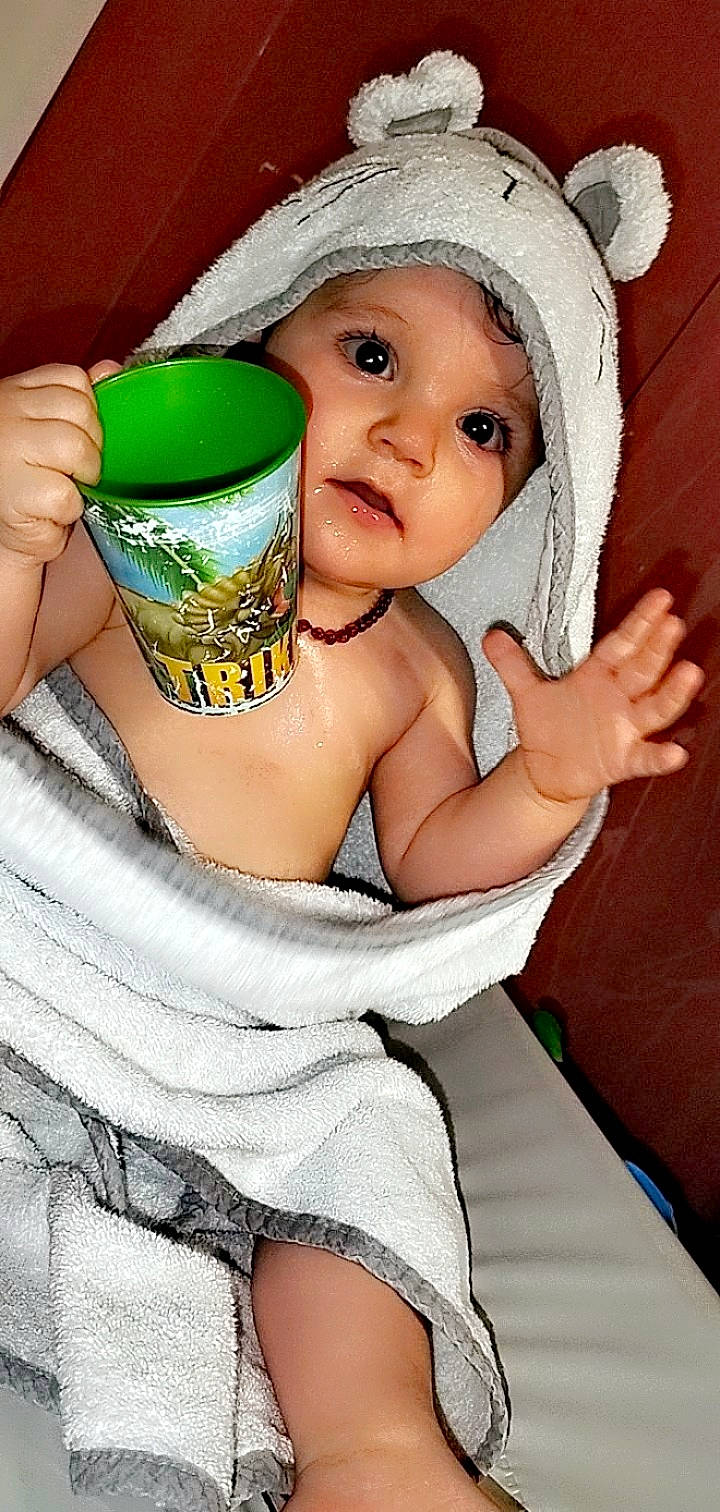 Leona a rejoint le concours — aidez-le/la à gagner de superbes lots ! arm, baby, baby_toddler_clothing, cap, chair, child, comfort, cup, drinkware, eyelash, fashion_accessory, finger, fun, hand, happy, headwear, person, serveware, smile, thigh