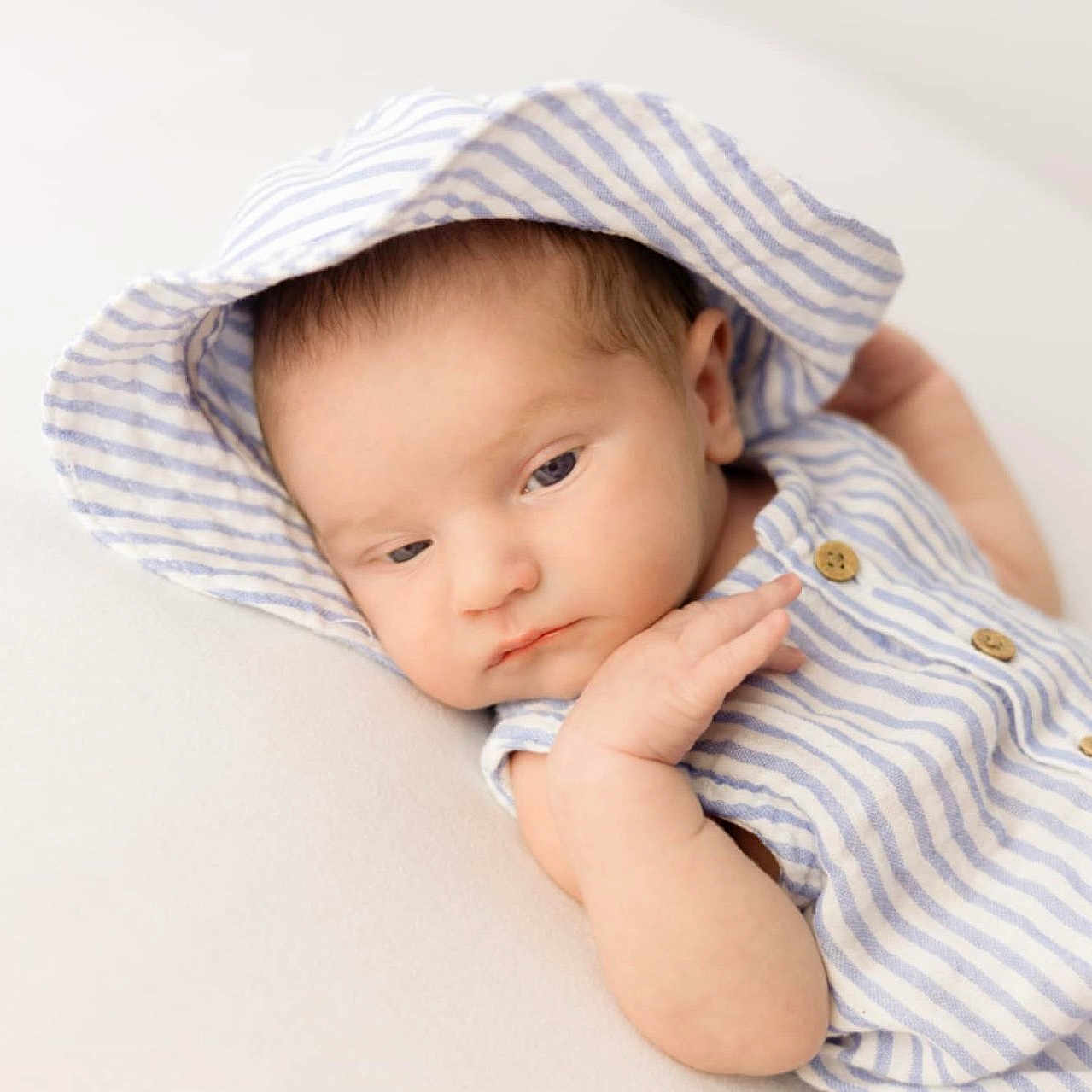 Georgie-Lee is registered to the contest to win money with this photo: baby, blue, child, closeup, cute, expression, face, hood, indoors, infant, newborn, peaceful, portrait, resting, skin, sleepy_eyes, small_hand, soft_surface, striped_clothing, white