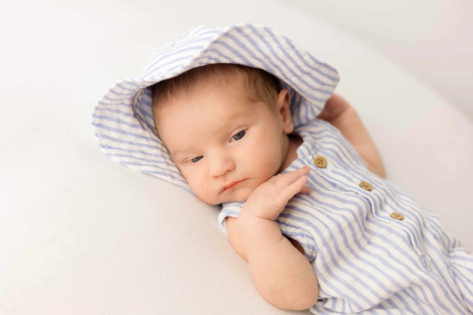 Georgie-Lee is registered to the contest to win money with this photo: baby, blue, child, closeup, cute, expression, face, hood, indoors, infant, newborn, peaceful, portrait, resting, skin, sleepy_eyes, small_hand, soft_surface, striped_clothing, white