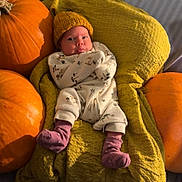 Frankie Jay is registered to the contest to win money with this photo: baby, infant, blanket, pumpkin, yellow_hat, onesie, purple_socks, couch, autumn, orange, cozy, indoor, portrait, child, cute, soft_texture, relaxing, seasonal, warm, smiling