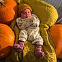 baby, infant, blanket, pumpkin, yellow_hat, onesie, purple_socks, couch, autumn, orange, cozy, indoor, portrait, child, cute, soft_texture, relaxing, seasonal, warm, smiling