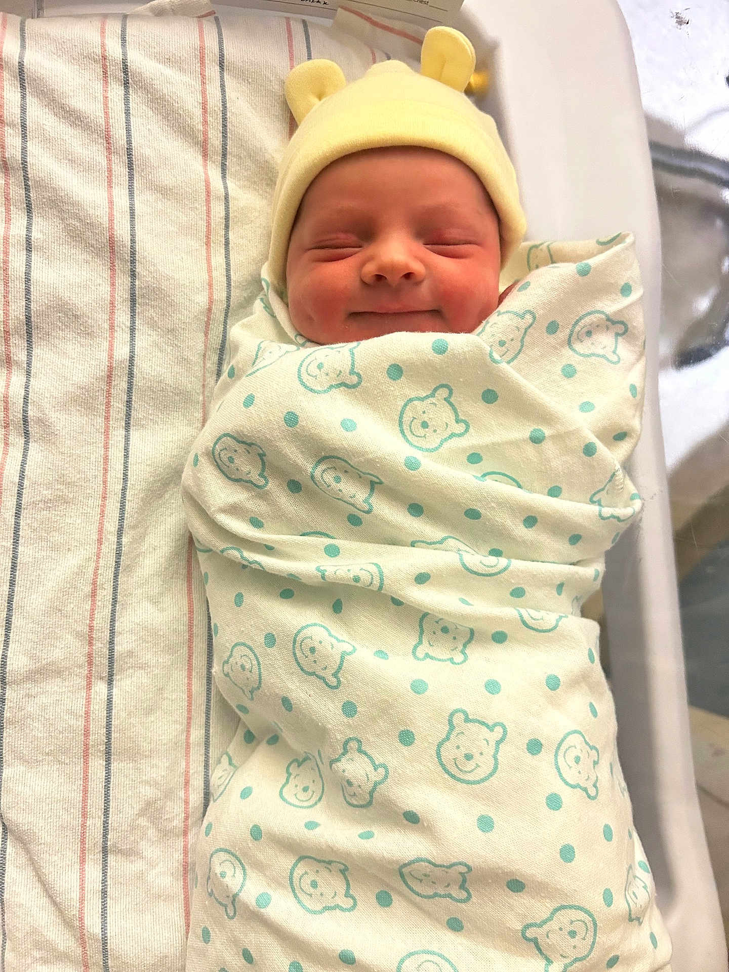 Elijah joined the competition — help win amazing prizes! newborn, baby, swaddled, blanket, hat, smiling, face, infant, hospital, bed, striped_blanket, cute, bear_pattern, yellow_hat, sleeping, cozy, child, portrait, wrapped, peaceful