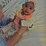 Nessa joined the competition — help win amazing prizes! adult, arm, baby, bed, bedding, bracelet, child, cozy, family, floral_pattern, headband, home, indoors, infant, pink_outfit, portrait, sitting, smiling, wide_eyed, yellow_clothing