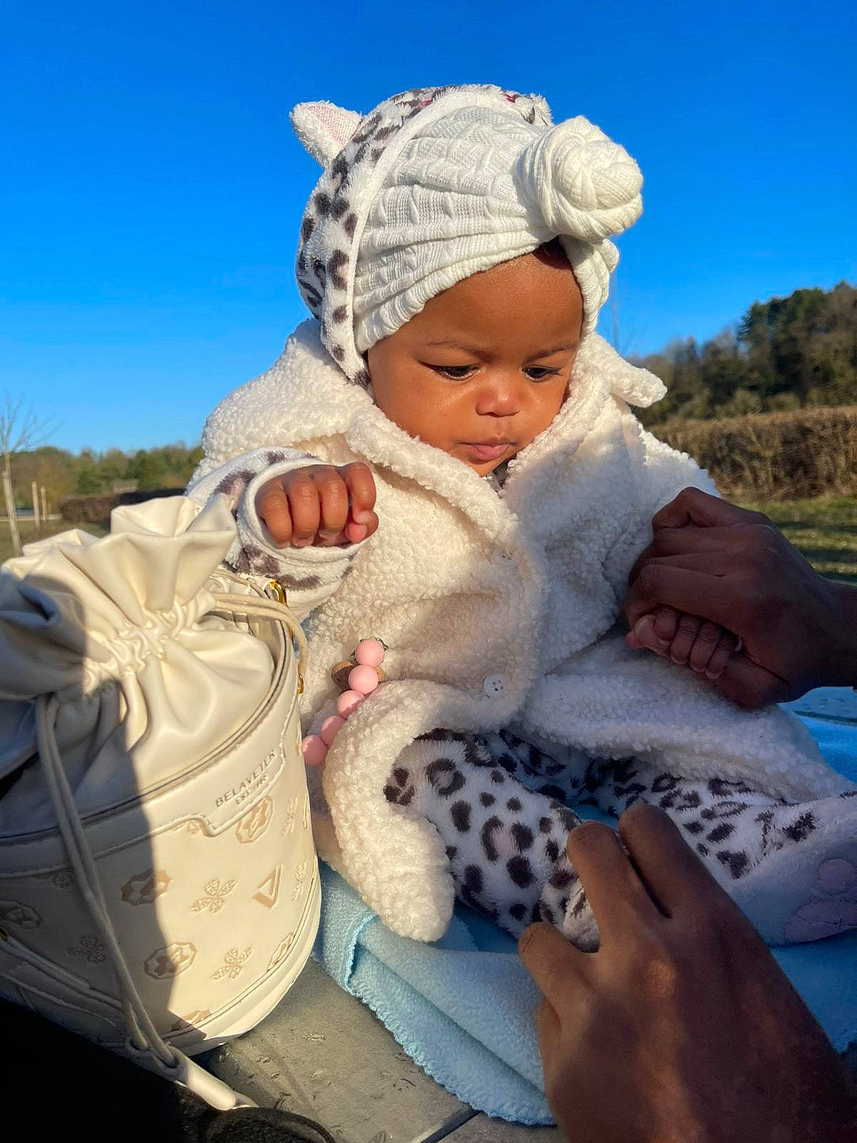 Aaliyah a rejoint le concours — aidez-le/la à gagner de superbes lots ! baby, cap, child, comfort, fun, fur, grass, happy, headwear, landscape, leisure, people_in_nature, person, plant, rock, sitting, sky, toddler, toy, tree