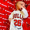 Muhammad is registered to the contest to win money with this photo: baby, infant, onesie, clothing, red_blanket, sports_team, chicago_bulls, logo, face, hand, lying_down, curious, cute, advertisement, pattern, soft_fabric, portrait, child, closeup, bright_colors