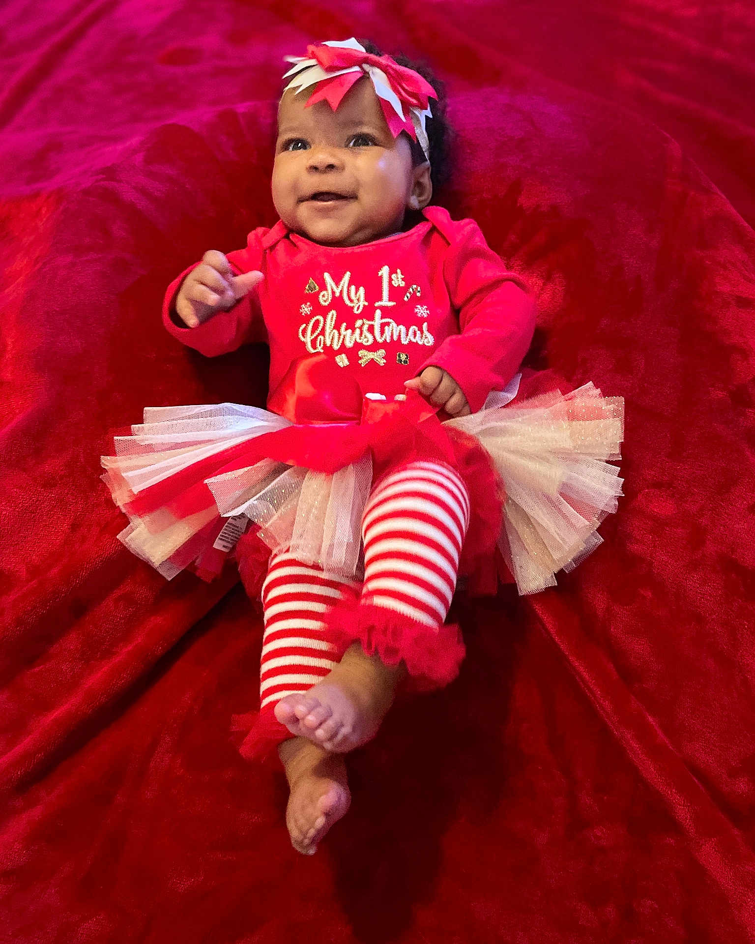 Ki'Mani joined the competition — help win amazing prizes! baby, blanket, bow, celebration, child, christmas, cute, feet, festive, happy, headband, holiday, infant, lying_down, portrait, red_clothing, smile, striped_leggings, toddler, tutu