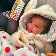 Ki'Mani is registered to the contest to win money with this photo: baby, blanket, car_seat, child, closeup, clothing, cozy, cute, face, happy, hooded_jacket, indoor, infant, infant_clothing, newborn, person, polka_dots, sitting, smile, warm