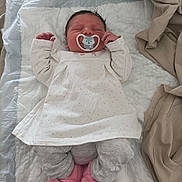 Ambre a rejoint le concours — aidez-le/la à gagner de superbes lots ! baby, newborn, sleeping, pacifier, white_dress, gray_pants, pink_slippers, unicorn_slippers, blanket, bed, infant, person, cute, indoors, soft, resting, child, cozy, sleep, wearing