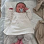 baby, newborn, sleeping, pacifier, white_dress, gray_pants, pink_slippers, unicorn_slippers, blanket, bed, infant, person, cute, indoors, soft, resting, child, cozy, sleep, wearing