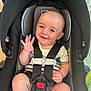 baby, car_seat, smiling, waving, infant, child, seatbelt, safety_harness, indoor, cute, happy, person, head, face, clothing, striped, skin, arm, leg, toy