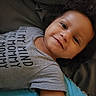 Reign joined the competition — help win amazing prizes! baby, child, infant, smiling, portrait, close_up, lying_down, bed, blanket, gray_shirt, clothing, curly_hair, brown_skin, face, eyes, nose, mouth, indoors, cozy, happy