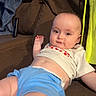 baby, child, infant, couch, brown_couch, shirt, blue_shorts, relaxed, indoor, home, furniture, person, face, skin, legs, hand, expression, clothing, casual, comfort