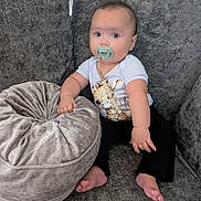 Isla Rose joined the competition — help win amazing prizes! baby, pacifier, couch, cushion, infant, child, clothing, sitting, indoors, cute, giraffe_print, barefoot, plush, face, expression, person, furniture, comfort, home, relaxation