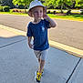 Christopher is registered to the contest to win money with this photo: blue_tshirt, boy, bucket_hat, casual_clothing, child, daylight, greenery, nature, outdoor, pavement, person, road, shadow, shorts, sidewalk, summer, sunny, trees, walking, yellow_shoes
