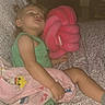 toddler, sleeping, blanket, plush_toy, pink, green_clothing, child, indoor, nap, comfort, couch, patterned_fabric, peaceful, soft_toy, rest, young_child, furniture, cozy, cute, relaxation