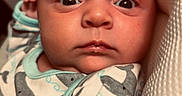 Sawyer is registered to the contest to win money with this photo: newborn, baby, child, infant, portrait, face, eyes, wide_eyed, indoors, onesie, clothing, swaddle, cushion, fabric, close_up, sitting, looking_at_camera, cozy, photography, head