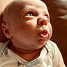 baby, infant, child, portrait, close_up, face, eyes, looking_up, curious, awake, mouth, nose, skin, bald, onesie, clothing, indoor, warm_lighting, sunlight, photography