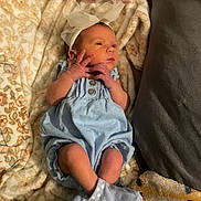 Mazzie is registered to the contest to win money with this photo: newborn, baby, infant, blue_outfit, headband, bow, blanket, cushion, sock, lying_down, soft_texture, cozy, small_hands, portrait, indoors, cute, sleepy, resting, child, person
