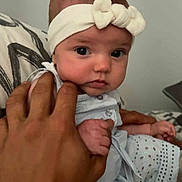 Luna participe au concours pour gagner de l'argent avec cette photo : baby, headband, hand, face, infant, clothing, person, cute, portrait, white, skin, fingers, holding, sitting, bed, pillow, indoor, expression, young, newborn