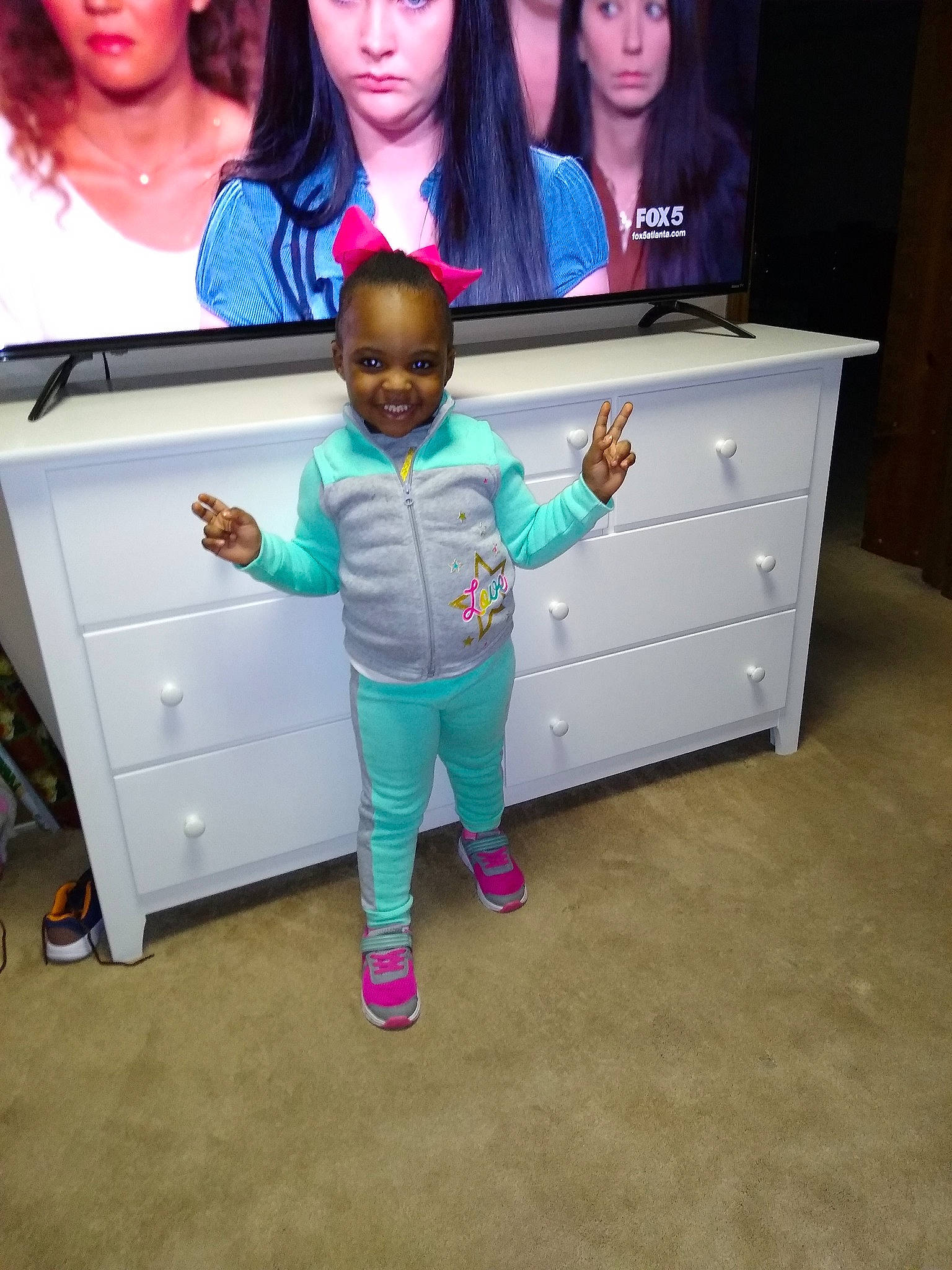 Tori is registered to the contest to win money with this photo: baby, child, drawer, electronic_device, face, footwear, fun, furniture, joy, leisure, person, pink, play, room, shoe, skin, smile, standing, t_shirt, table