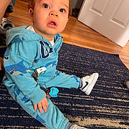Amir joined the competition — help win amazing prizes! toddler, child, indoor, blue_hoodie, shark_pattern, sneakers, carpet, wooden_floor, door, curious, expression, sitting, young_child, playful, pacifier, clothing, floor, person, footwear, casual
