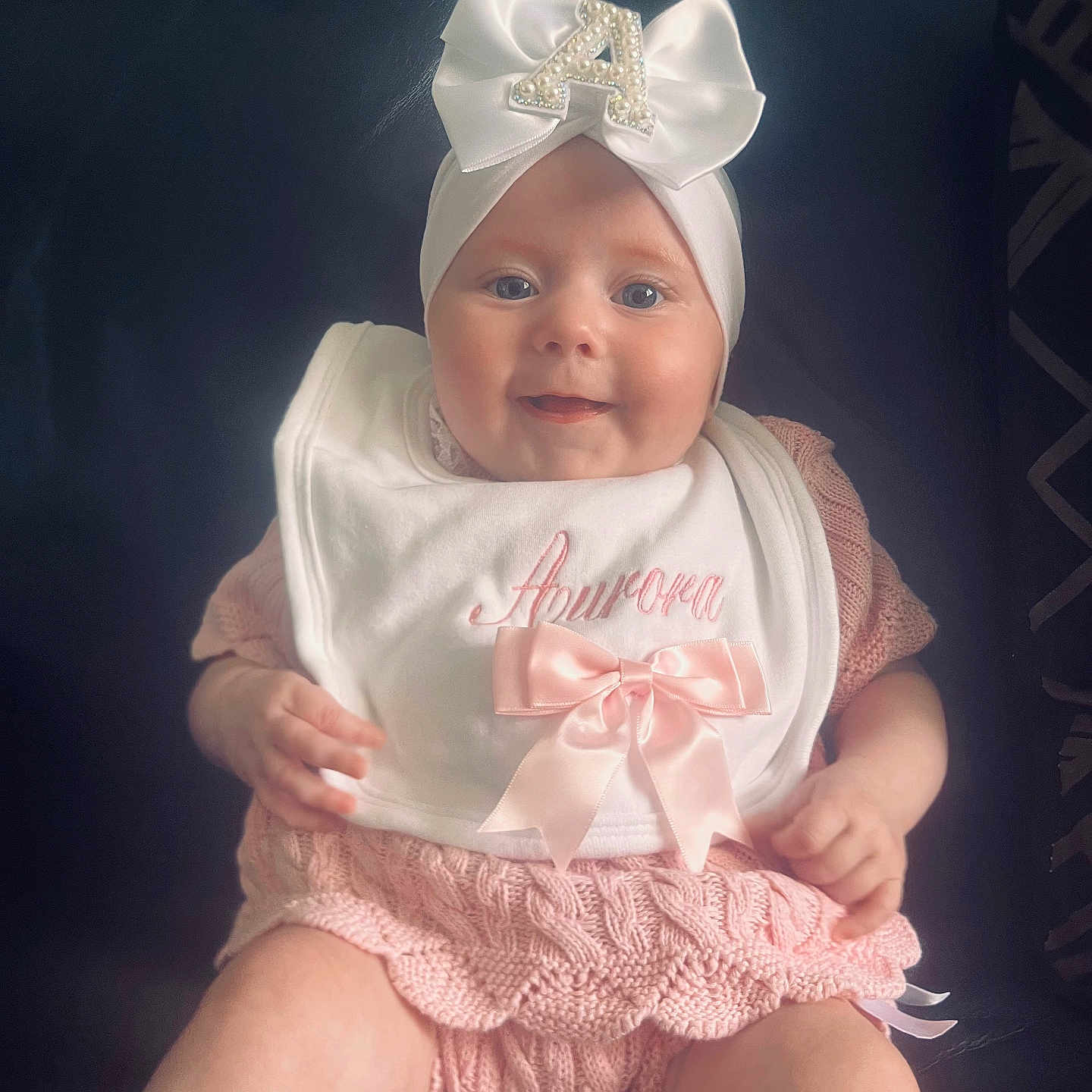 Aurora joined the competition — help win amazing prizes! accessory, apparel, baby, baby_girl, bib, bow, child, closeup, cute, face, happy, headband, indoor, infant, knitted, person, pink_clothing, portrait, sitting, smiling