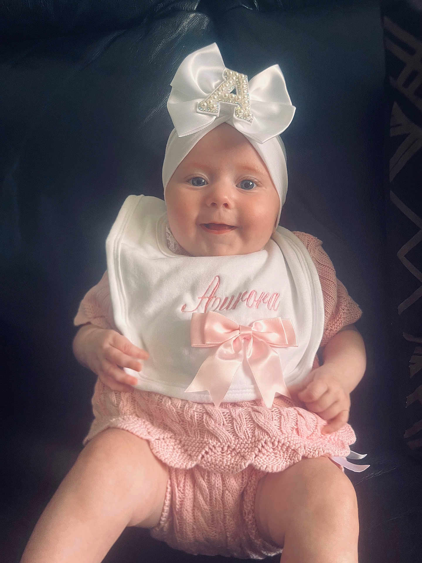 Aurora joined the competition — help win amazing prizes! baby, infant, smiling, pink_clothing, knitted, headband, bow, bib, sitting, cute, portrait, child, face, happy, indoor, person, apparel, accessory, baby_girl, closeup