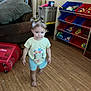 toddler, child, barefoot, pigtails, indoor, wooden_floor, toy_storage, toys, couch, shirt, shorts, person, living_room, plastic_bin, floor, furniture, walking, hair, face, home