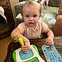 toddler, child, toy, educational_toy, table, dog, couch, person, living_room, wood_floor, small_dog, curly_hair, playing, indoor, pink_shirt, pen, technology, cute, focus, animal