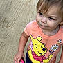toddler, child, person, hairbrush, winnie_the_pooh, tshirt, pink, yellow, blue_shorts, outdoor, sand, tire_tracks, curly_hair, cute, standing, looking_away, small_hand, casual_clothing, daylight, playful