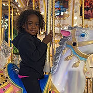 Kemil participe au concours pour gagner de l'argent avec cette photo : amusement_ride, black_clothing, carnival, carousel, child, colorful, curly_hair, entertainment, evening, fun, golden_pole, happy, horse, lights, outdoor, person, portrait, ride, smile, toy