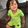Ayden participe au concours pour gagner de l'argent avec cette photo : bracelet, bright, brown_furniture, casual, child, couch, cozy, curly_hair, cute, green_clothing, happy, indoor, living_room, panda_pattern, person, portrait, sitting, smile, socks, young