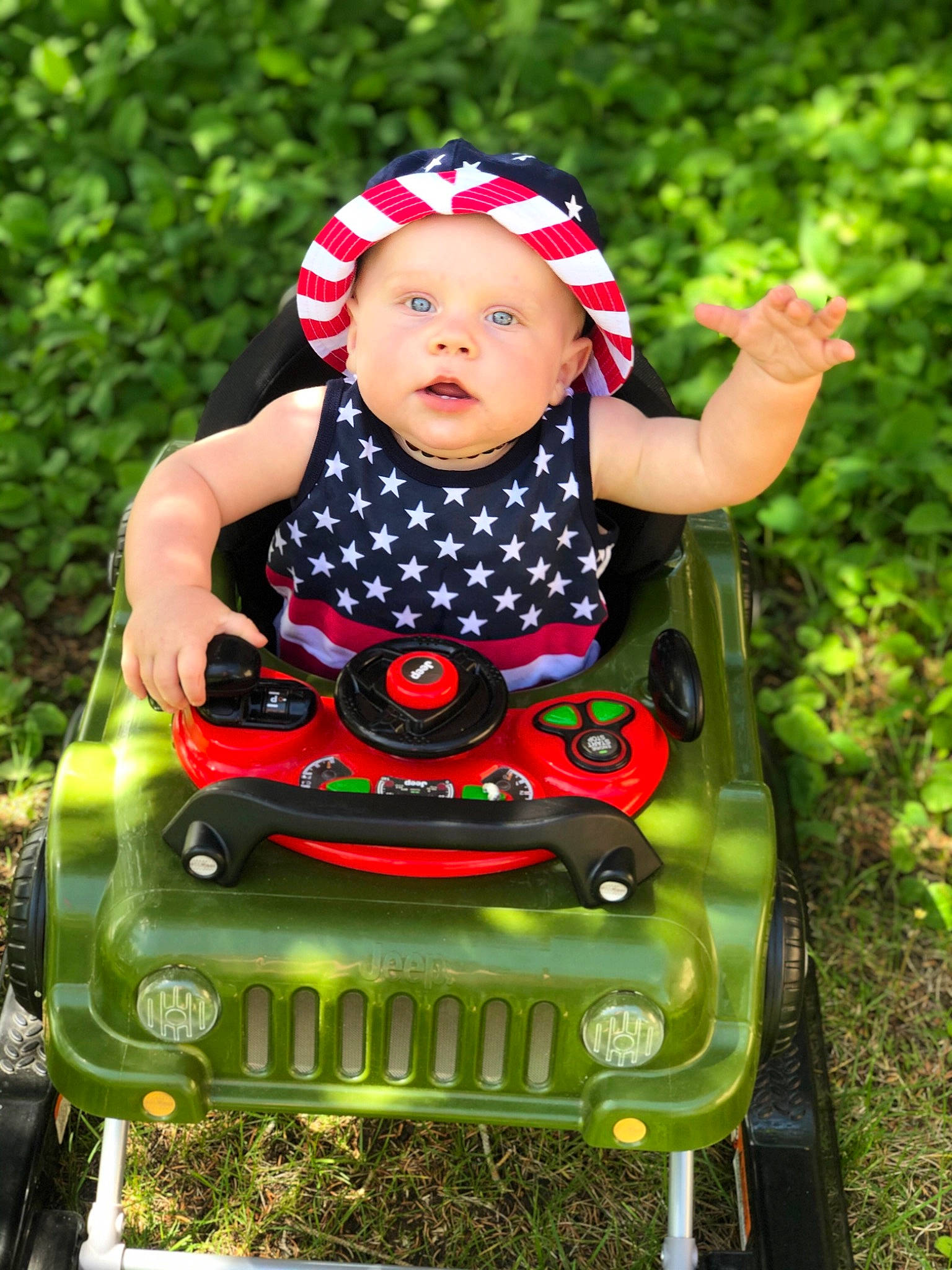 Karsyn is registered to the contest to win money with this photo: baby, baby_products, baby_toddler_clothing, child, fun, grass, happy, headwear, person, plant, play, product, riding_toy, sitting, smile, toddler, vehicle