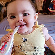 Kaiya is registered to the contest to win money with this photo: baby, child, infant, yellow_clothing, winnie_the_pooh, piglet, hairbrush, pigtails, smiling, indoors, cute, playful, person, sitting, face, eyes, hand, chewing, bed, toy