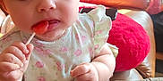 Kaiya joined the competition — help win amazing prizes! baby, child, lollipop, couch, cushion, quilt, curly_hair, dress, indoor, person, cute, sweet, food, snack, happy, face, hand, sitting, plush, portrait