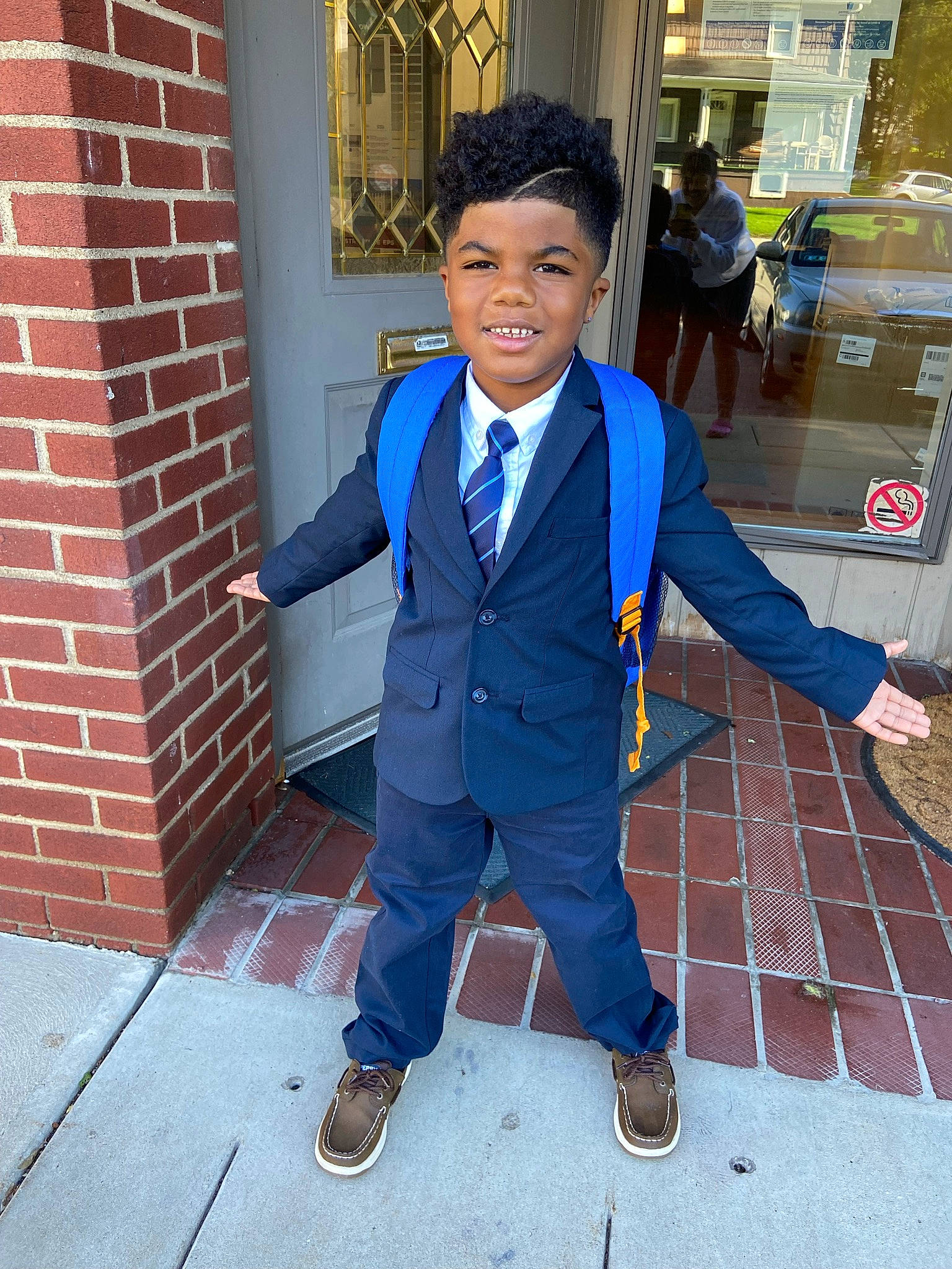 Maximus is registered to the contest to win money with this photo: blazer, brick, brickwork, collar, denim, dress_shirt, electric_blue, flooring, footwear, formal_wear, gesture, joy, person, school_uniform, shoe, sleeve, smile, suit, tie, uniform