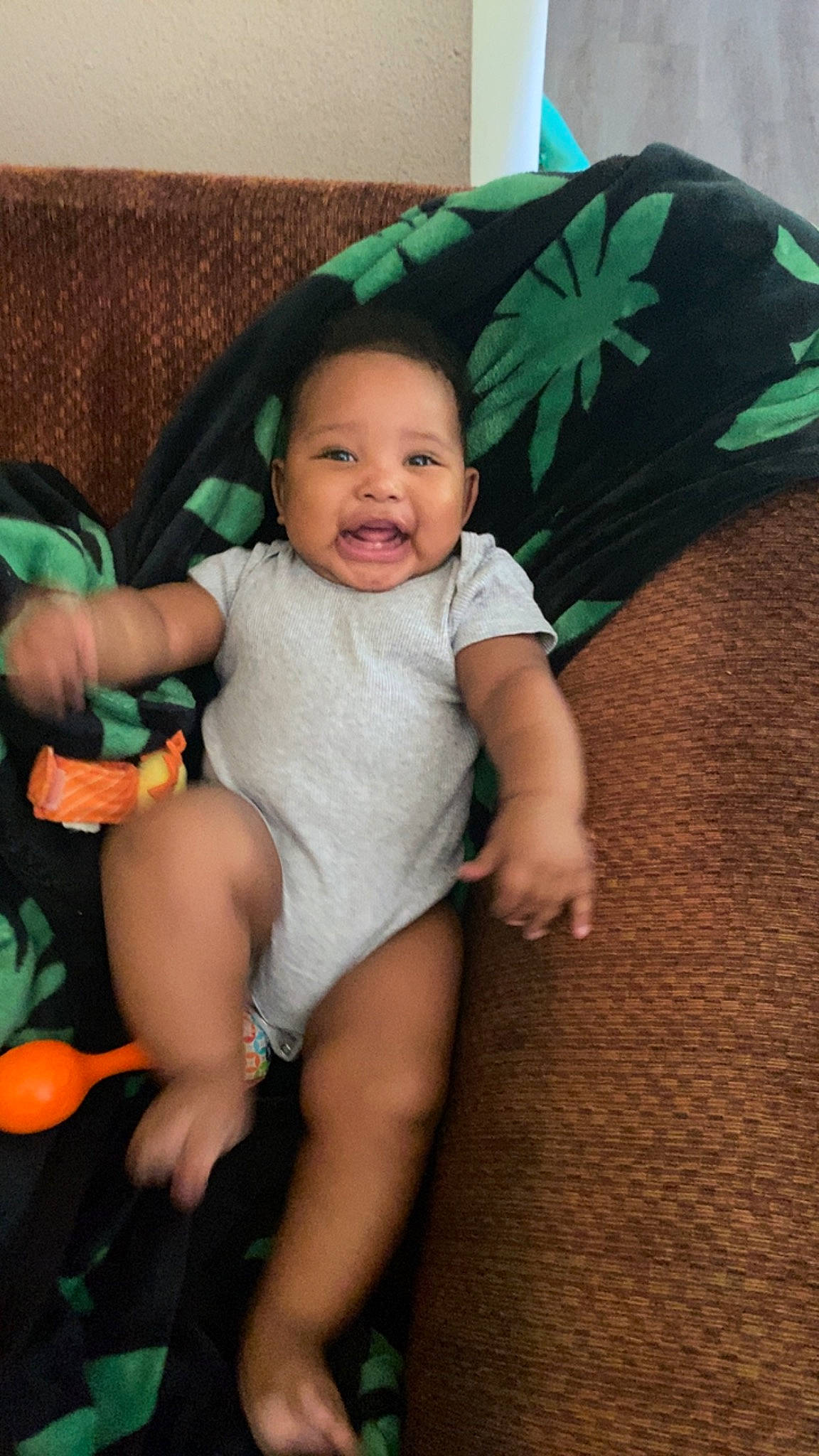 Caleb is registered to the contest to win money with this photo: baby_toddler_clothing, cheek, comfort, eye, finger, green, happy, head, human_body, iris, leaf, mammal, mouth, organ, person, skin, smile, textile, thigh, umbrella