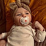 baby, infant, pacifier, headband, knitted_bow, clothing, cushion, yellow, beige, texture, soft, lying_down, indoors, cute, child, portrait, peaceful, comfort, baby_girl, wrapped