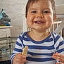 toddler, child, smiling, food, messy_face, striped_shirt, biscuit, hand, indoor, toy, stuffed_animal, elephant_toy, table, chair, face, happy, person, home, furniture, baby
