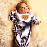 Augustin participe au concours pour gagner de l'argent avec cette photo : baby, infant, striped_clothing, onesie, bib, bear_patch, lying_down, fluffy_blanket, cream_color, soft_texture, newborn, cute, portrait, indoors, small_hands, face, head, footed_pajamas, cozy, sleepwear