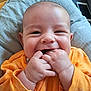 Augustin a rejoint le concours — aidez-le/la à gagner de superbes lots ! baby, infant, smiling, orange_clothing, hands, fingers, blanket, face, cute, cheerful, lying_down, indoors, plush_toy, smartphone, soft_texture, closeup, expression, person, child, happy