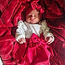 baby, infant, sleeping, red_blanket, red_skirt, headband, bow, white_sleeves, cozy, soft_texture, cute, newborn, hands, portrait, resting, child, clothing, fabric, indoor, closeup