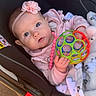 adorable, baby, baby_girl, blanket, blue_eyes, car_seat, child, child_seat, closeup, clothing, comfort, cute, indoors, infant, person, pink_headband, seat, soft_lighting, toy_ball, young_child