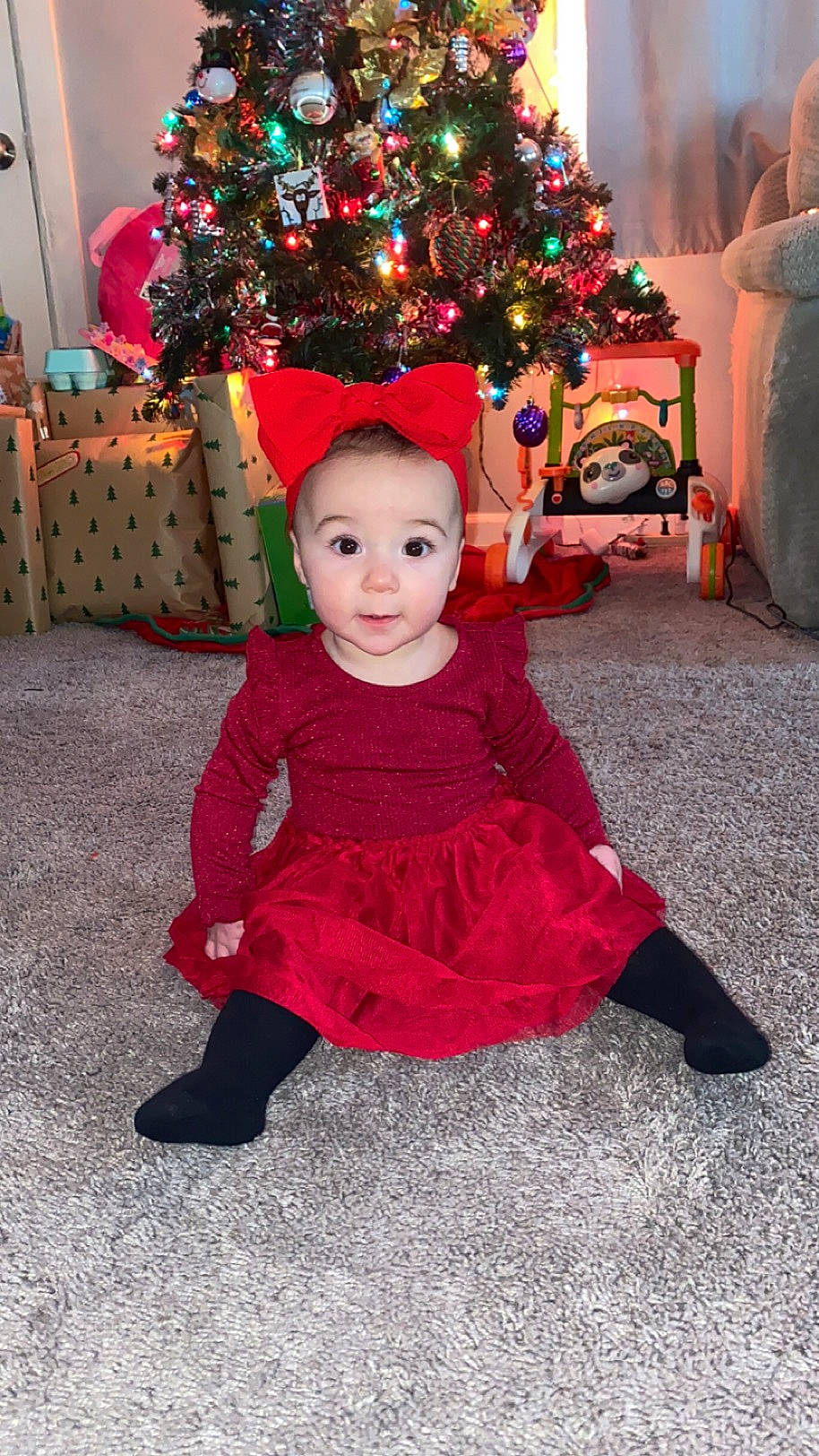 Violet is registered to the contest to win money with this photo: baby_toddler_clothing, child, christmas, christmas_decoration, christmas_eve, christmas_ornament, christmas_tree, conifer, event, fun, happy, head, holiday, holiday_ornament, magenta, ornament, person, plant, toddler, tradition