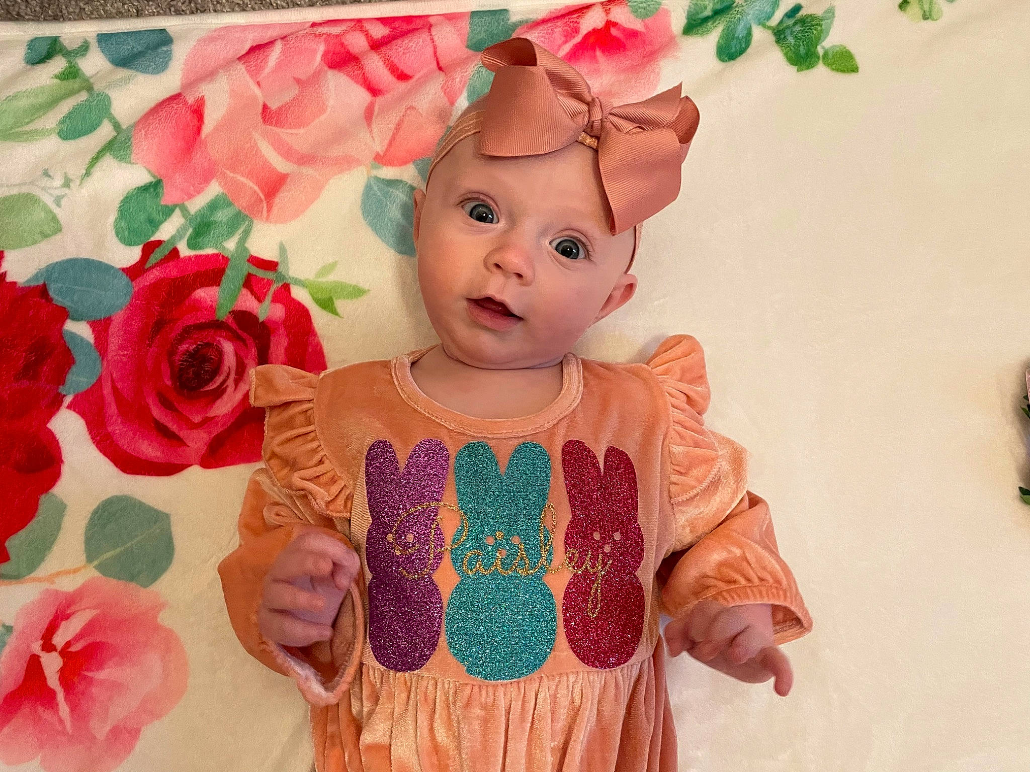 Paisley is registered to the contest to win money with this photo: art, baby, baby_toddler_clothing, cheek, dress, flower, happy, head, headgear, headwear, human_body, hybrid_tea_rose, pattern, peach, person, petal, pink, plant, rose, skin