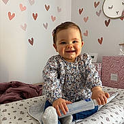 Lya a rejoint le concours — aidez-le/la à gagner de superbes lots ! baby, child, smiling, bottle, floral_clothing, hair_clip, socks, changing_pad, nursery, heart_wall_decals, bunny_wall_art, pink, brown, indoor, cute, happy, infant, sitting, patterned, toy